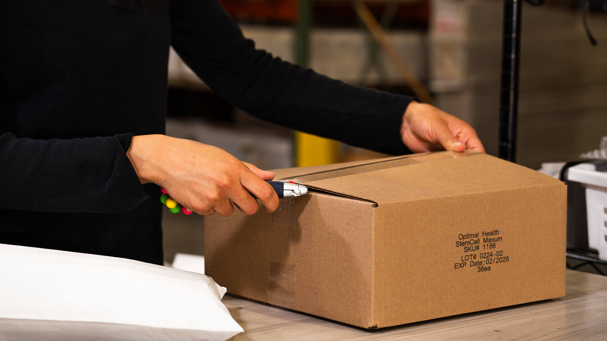 person opening a cardboard box with box cutter